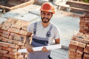 Holding, the document. Handsome Indian man is on the construction site photo
