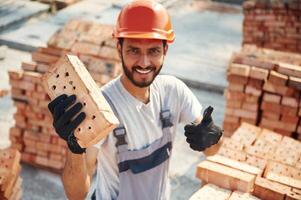 Close ,up, view ,of brick that is in the, hands. Handsome Indian man is on the construction site photo
