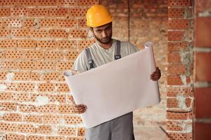 Holding the, document. Handsome Indian man is on the construction site photo