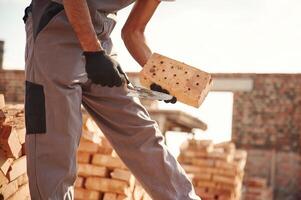 With, brick in hands. Close up view of man that is working on the construction site photo