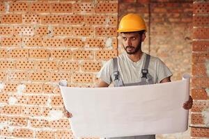 Holding the document. Handsome Indian man is on the construction site photo