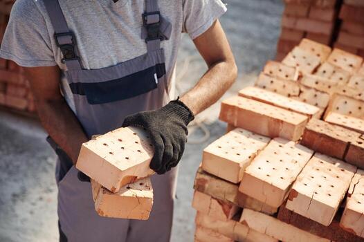 With brick in hands. .Close, up view of man that is working on the construction site photo