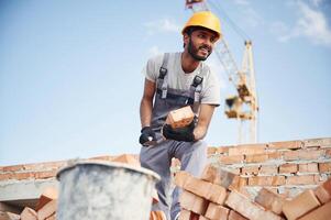 Blue, sky, and crane is behind. Handsome Indian man is on the construction site photo