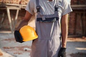 Holding yellow colored hard hat. Close up view of man that is working on the construction site photo