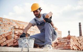 Bucke,t on ,the ground, holding a brick. Handsome Indian man is on the construction site photo