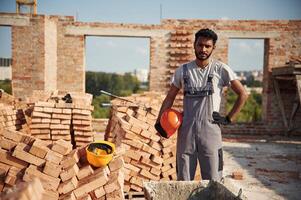 In, grey uniform. Handsome Indian man is on the construction site photo
