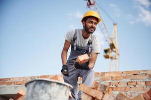 Blue sky, and crane is behind. Handsome Indian man is on the construction site photo