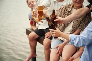 Group, of ,friends are sitting near ,the lake with beer in hands photo