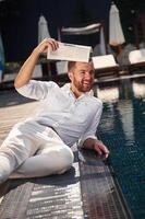 Holding newspaper. Handsome man in formal clothes is in the pool photo
