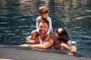 In the water. Happy family of father, mother and son are in the pool photo