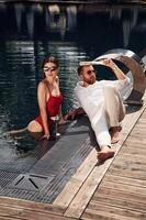 With newspaper in ,hand. Man with woman is in the pool together photo
