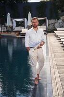 Business look, standing. Handsome man, in formal clothes is in the pool photo