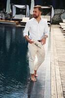 Business look,, standing. Handsome man in formal clothes is in the pool photo