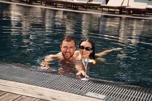 Embracing each other., Man, with woman ,is in the pool together photo
