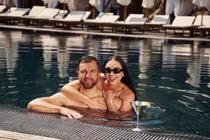 Embracing each other. Man, with woman ,is in the pool together photo