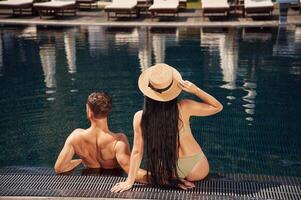 Rear view.. Man with woman is in the pool together photo