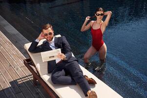 Reading the newspaper. Man with woman, is in the pool together photo