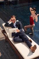 Reading, the newspaper. Man, with, woman is in the pool together photo