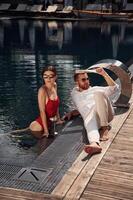 With ,newspaper in ,hand. Man with woman is in the pool together photo