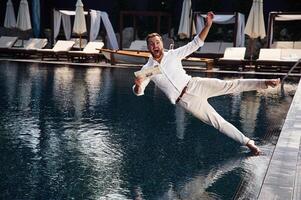 Falling into the water. Handsome man in formal clothes is in the pool photo