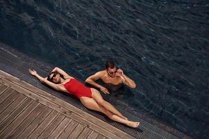 Woman ,is lying down. Man is in the pool. photo
