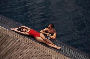 Woman is lying down. Man is ,in the pool photo