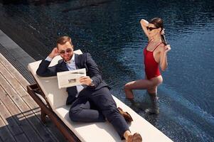 Reading, the newspaper. Man with woman is in the pool together photo
