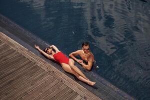 Woman is lying down. Man is in the pool. photo