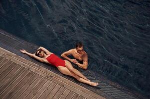 Woman is lying ,down. Man is in the pool photo