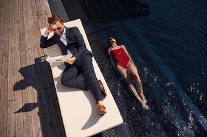 Reading the ,newspaper. Man with woman is in the pool together photo