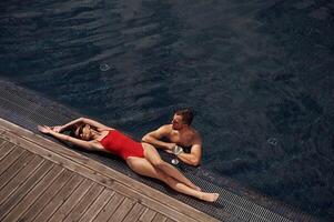 Woman is lying down.. Man is in the pool photo