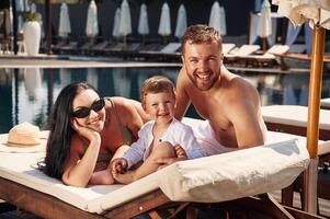 Conception of, vacation. Happy family of father, mother and son are in the pool photo
