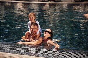 In the water. Happy family of father,, mother and son are in the pool photo