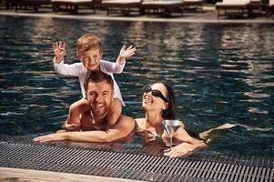 Smiling, having, fun.. Happy family of father, mother and son are in the pool photo