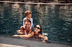 In the, water. Happy family of father, mother and son are in the pool photo