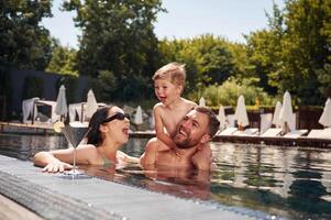 Having fun... Happy family of father, mother and son are in the pool photo