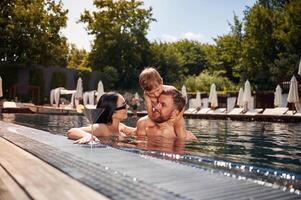 Having fun. Happy, family of father, mother and son are in the pool photo