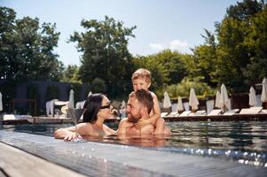 Having fun.. Happy family of father, mother and son are in the pool photo