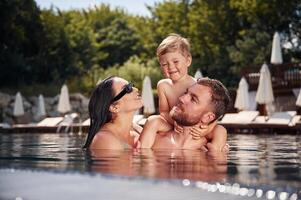Having, fun. Happy family of father, mother and son are in the pool photo