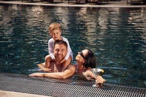 In, the water. Happy family of father, mother and son are in the pool photo