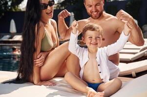 Happy, family of father, mother and son are in the pool photo
