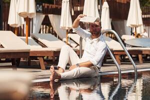 Sitting, taking a rest. Handsome man in formal clothes is in the pool photo