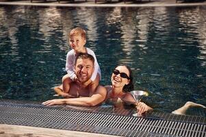 Front, view. Happy, family ,of father, mother and son are in the pool photo