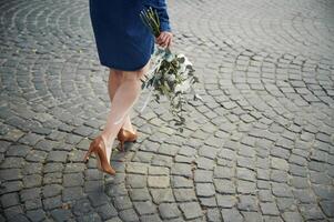 Legs, walking forward. Close up view of woman that is with flowers in hands photo