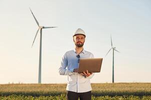 With laptop in hands., Service engineer, is on the field with windmills photo