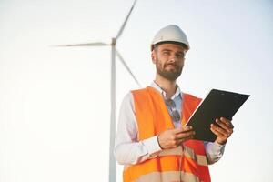Black, notepad ,in hands. Service engineer is on the field with windmills photo