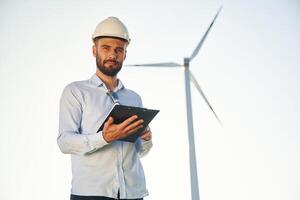 Front view. Service engineer, is on the field with windmills photo
