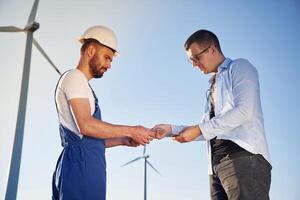 Making dea,l with businessman. Service engineer is on the field with windmills photo