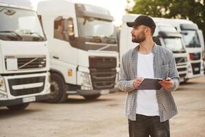Notepad, in hands. Young truck, driver in casual clothes photo