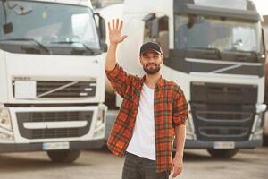 Hello gesture by a hand. Young truck driver in casual clothes photo